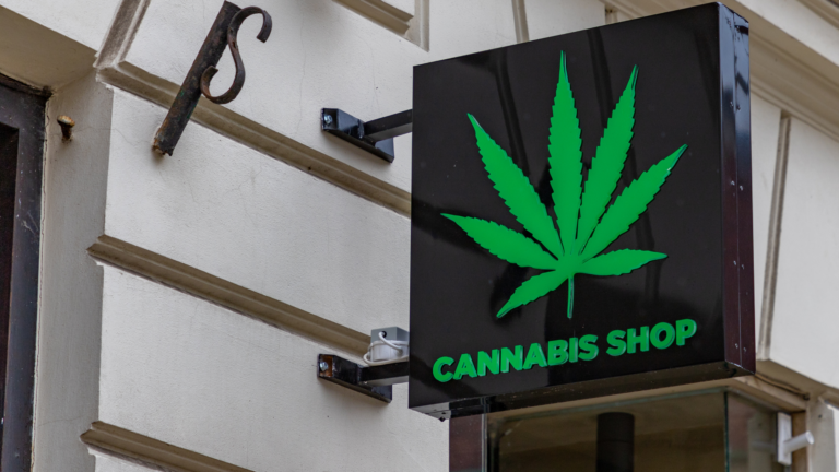 Cannabis shop storefront sign with green weed leaf.