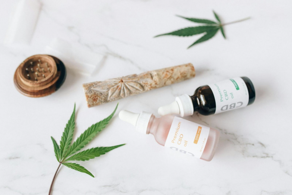 Cannabis leaves and cbd products laid on white table